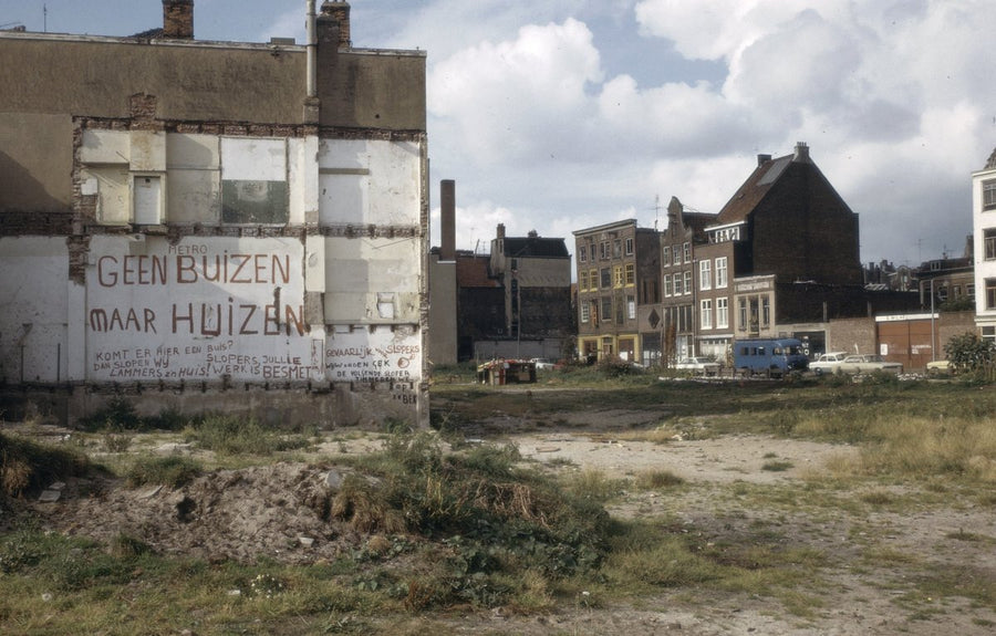 Amsterdam demolition site with the slogan 'Geen buizen maar huizen' painted on a wall