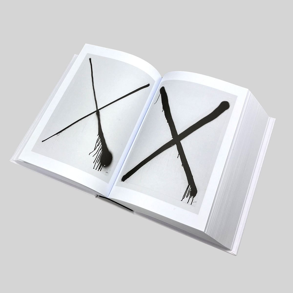 MONOMANIA, open spread with two spray-painted crosses, one thin and one bold